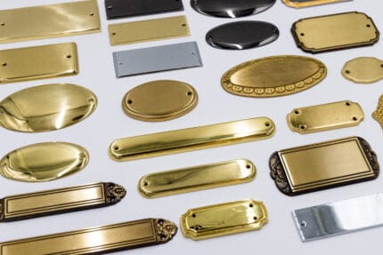 Forskellige typer metalnavneskilte på hvid baggrund.