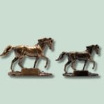 To bronzeskulpturer af heste på grøn baggrund.