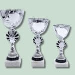 Tre sølvpokaler på grøn baggrund.