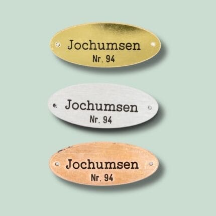 Tre ovale navneskilte i forskellige metaller