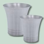 To sølvfarvede metalvaser på grøn baggrund.