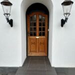 Trædør med buet indgang og lanterner på væggen.