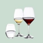 Tre vinglas med vin og vand på grøn baggrund.