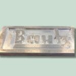 Metalplakette med indgraveret tekst Bautz på grøn baggrund.