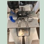 Maskine bearbejder metaldel med blå håndtag