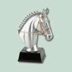 Sølvfarvet hestehovedskulptur på sort sokkel